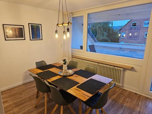 a dining room table with chairs and a large window at Deisterquartier, Ferienwohnung am Naherholungsgebiet in Barsinghausen