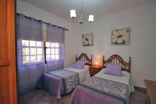 a bedroom with two beds and a window with a chandelier at Las Palmeras B in Arecida