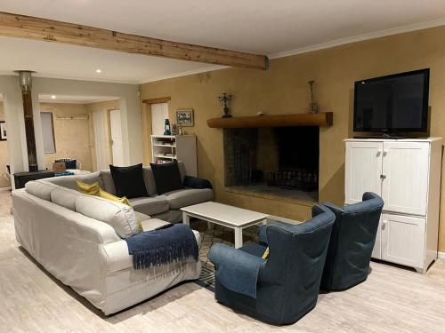 a living room with a couch and chairs and a tv at Beach front Rocky Pools in Bettyʼs Bay