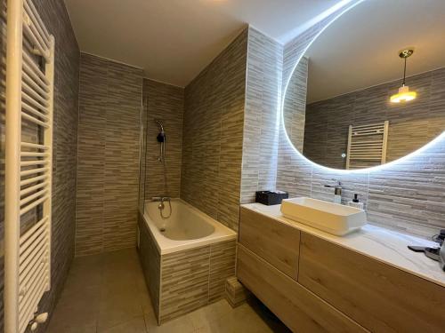 a bathroom with a sink and a tub and a mirror at Appartement Luxueux 3 pièces climatisé avec Terrasse, 5 couchages - 17ème Arrondissement de Paris in Clichy