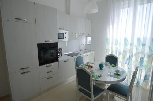 a white kitchen with a table and chairs and a kitchen with a stove at Balcone in Valle d'Itria in Martina Franca