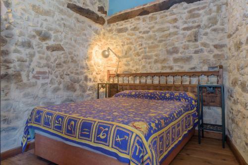 1 dormitorio con 1 cama en una pared de piedra en El Telar, en Rasines