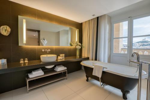 a bathroom with a tub and a sink and a mirror at InterContinental Marseille - Hotel Dieu by IHG in Marseille