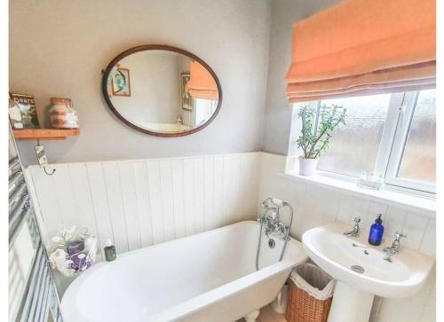 a bathroom with a tub and a sink and a mirror at Detached Country Bungalow in Wroughton