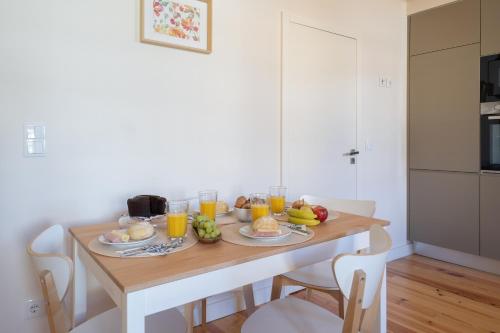 a table with breakfast foods and orange juice on it at Host Wise - Lovely & Cozy Duplex Flat in Porto