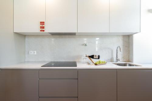 a white kitchen with a sink and white cabinets at Host Wise - Lovely & Cozy Duplex Flat in Porto