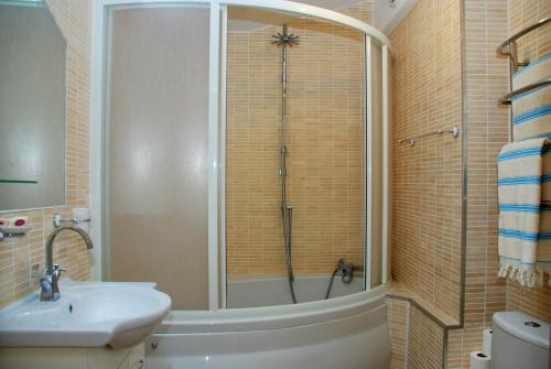キーウにあるKiev Pozniaky Apartmentのバスルーム(シャワー、シンク、バスタブ付)