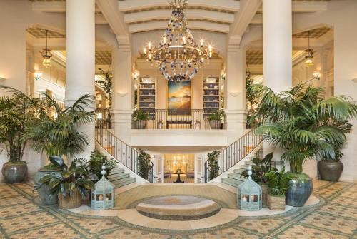 a large lobby with a chandelier and palm trees at Casa Del Mar in Los Angeles