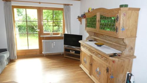 uma sala de estar com uma cozinha em madeira e uma televisão em Ferienwohnung Dillmann em Sachrang