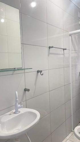 GL Pousada في غوارويا: حمام أبيض مع حوض ومرآة
