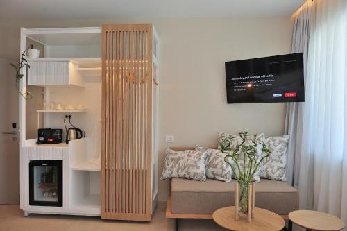 a living room with a couch and a tv on a wall at Salty Wave Suites in Skiathos Town