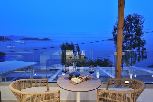 a table with two chairs and wine glasses on a balcony at Salty Wave Suites in Skiathos Town