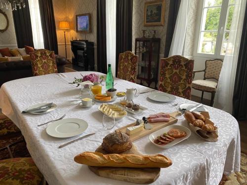una mesa con un mantel blanco con comida. en Le Grand Berger Chambres D'Hotes, 
