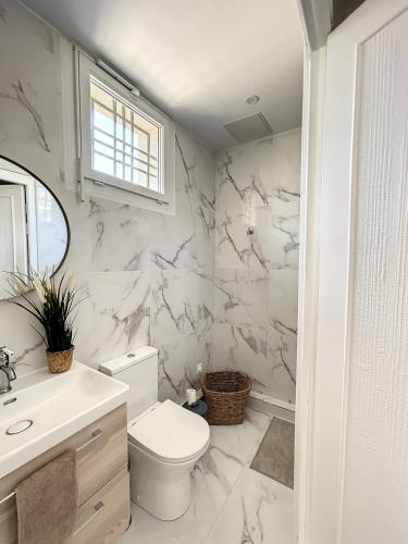 une salle de bain blanche avec des toilettes et un lavabo dans l'établissement Charmante maison de ville avec jardin, terrasse et terrain de pétanque, à Fos-sur-Mer