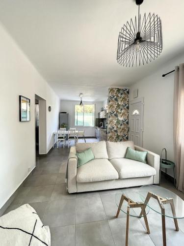 un salon avec un canapé blanc et une table dans l'établissement Charmante maison de ville avec jardin, terrasse et terrain de pétanque, à Fos-sur-Mer