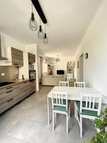 une cuisine et une salle à manger avec une table et des chaises blanches dans l'établissement Charmante maison de ville avec jardin, terrasse et terrain de pétanque, à Fos-sur-Mer