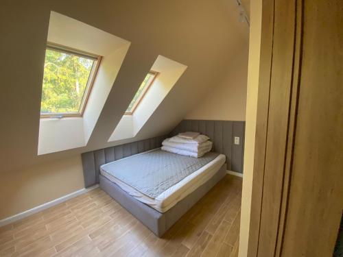 a small bedroom with a bed with two windows at Zakątek Śniardwy in Nowe Guty