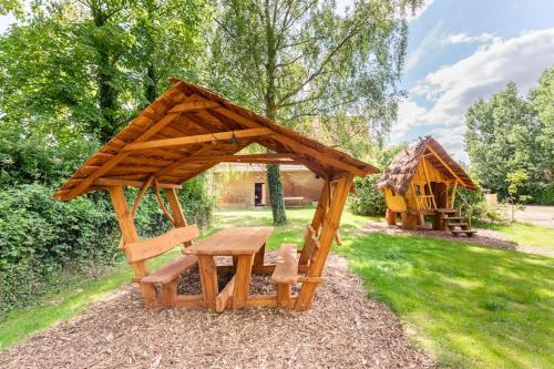 a wooden picnic table and a gazebo in a yard at Au pied du frêne in Herzeele