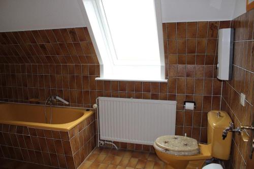 une salle de bain avec baignoire et toilettes et une fenêtre dans l'établissement Marschenblick-2, à Sankt Peter-Ording