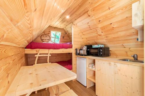 a log cabin kitchen with a table and a microwave at Au pied du frêne in Herzeele