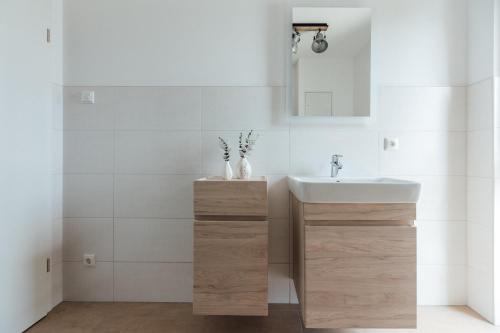 a white bathroom with a sink and a mirror at Exklusive Ferienwohnungen an der Havel in Werder