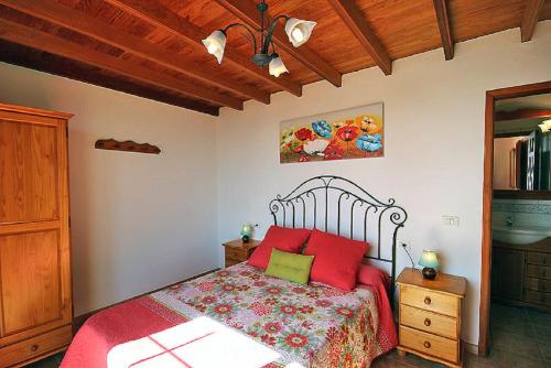 a bedroom with a bed with red and green pillows at Las Palmeras C in Arecida