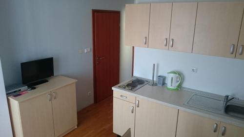 a kitchen with white cabinets and a flat screen tv at Guest House Lav in Primošten