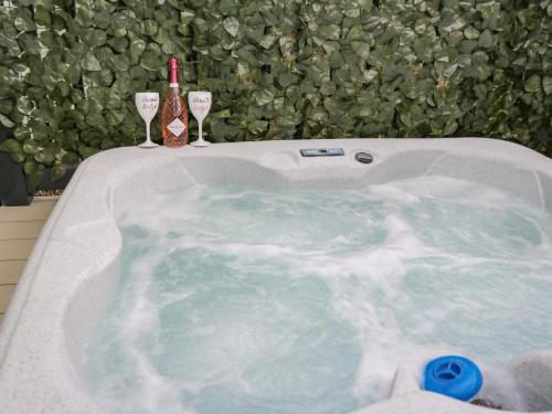 a bath tub with two glasses and a bottle of wine at Jean's Place in Ganton