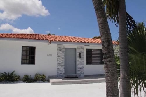 een wit huis met een deur en twee palmbomen bij Luxury Vacation House in Miami’s Center! in Miami
