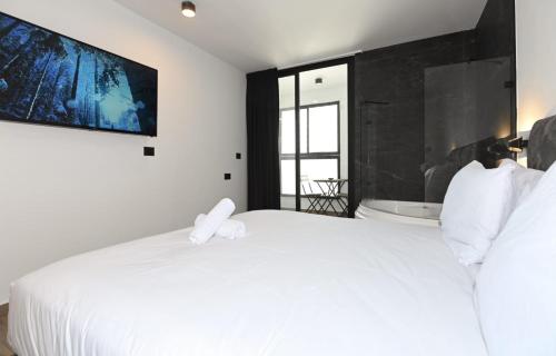a bedroom with a white bed and a tv on the wall at Selfie's Boutique Hotel in Tiberias