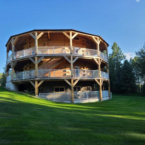 a large wooden building with balconies on a green field at Sundance Country Lodge B&B in Marlboro