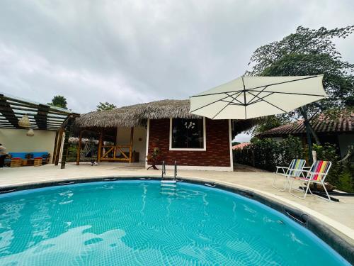 ein Pool mit Sonnenschirm und ein Haus in der Unterkunft Cabaña de Elsa in Olón