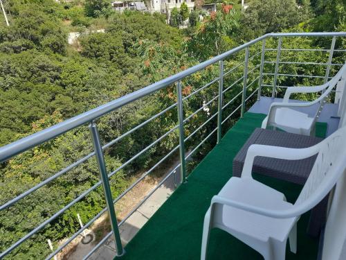 three white chairs on a balcony with trees at Nino Lux Apartments Ulcinj in Ulcinj