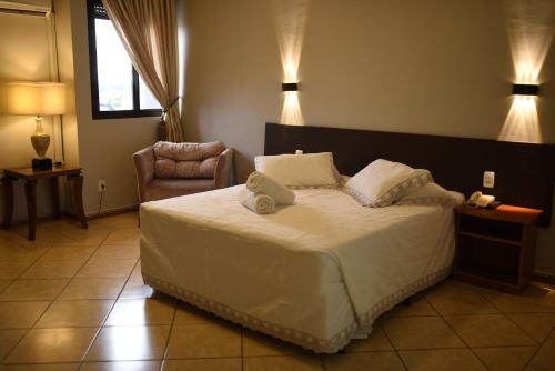 a bedroom with a bed and a chair and lights at Hotel Plaza Sul in Caràzinho