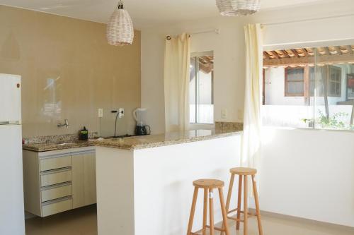 a kitchen with a counter and two stools at Condomínio Harmonia in Pipa