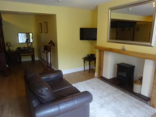 a living room with a leather couch and a fireplace at Claremont House in Saundersfoot