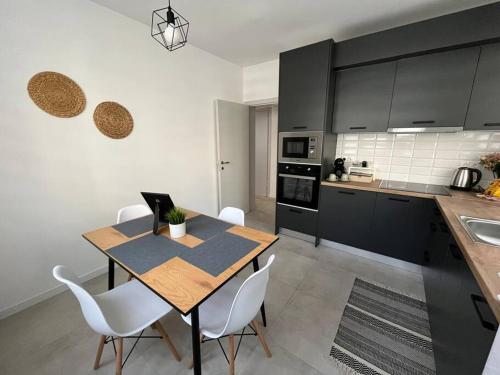 a kitchen with a wooden table and white chairs at Modern City Center 2 Bedroom Apartment in Sofia