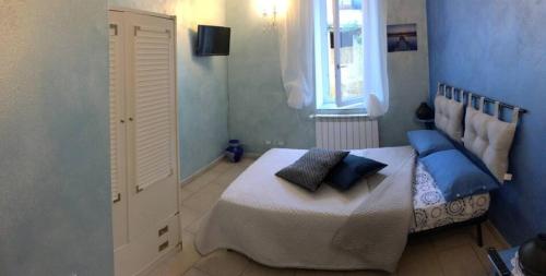 Un dormitorio con una cama con almohadas azules y una ventana en Home n Breakfast Ca' di Toni, en Testana