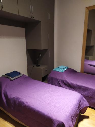 Dos camas en una habitación con sábanas moradas. en Palermo Apart Bulnes, en Buenos Aires