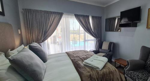Kairos Guesthouse Orania في Orania: غرفة نوم بسرير ونافذة وكرسي