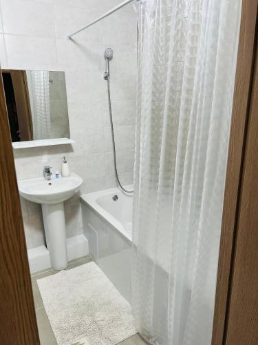 a white bathroom with a shower curtain and a sink at Апартаменты «Одесские традиции» in Odesa