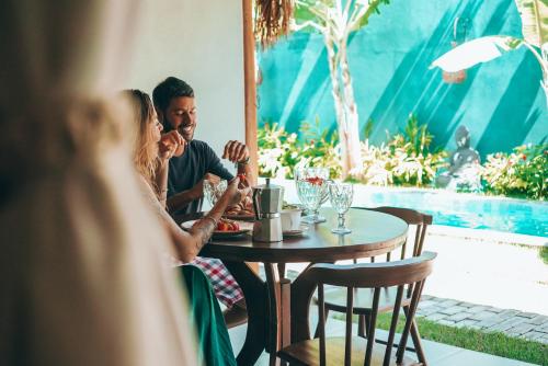 un homme et une femme assis à une table dans un restaurant dans l'établissement Tropicália chalés boutique, à Pipa