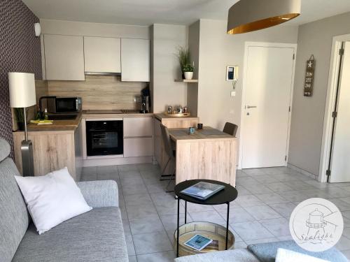 a living room with a couch and a kitchen at Appartement Sealight in De Haan