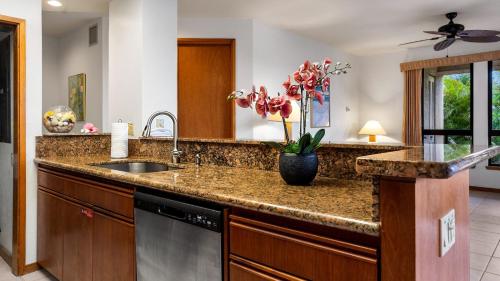 a kitchen counter with a sink and a vase of flowers at The Shores at Waikoloa 117 in Waikoloa