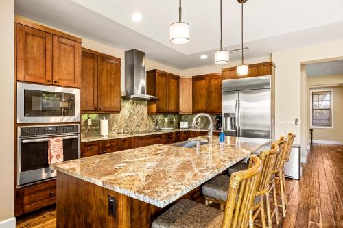 a kitchen with wooden cabinets and a marble counter top at Holua Kai 37 in Kailua-Kona