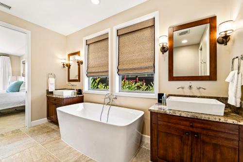 a bathroom with a tub and a sink and a mirror at Holua Kai 37 in Kailua-Kona