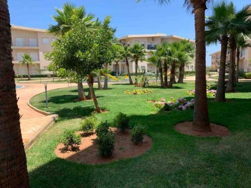 park z palmami i budynek w obiekcie Kenz Mehdia - Vue sur Piscine w mieście Kenitra