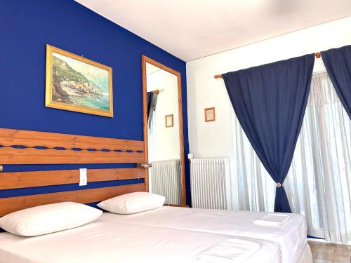 a bedroom with a blue wall and a bed at Bay Holiday Hotel & Spa in Karavómilos