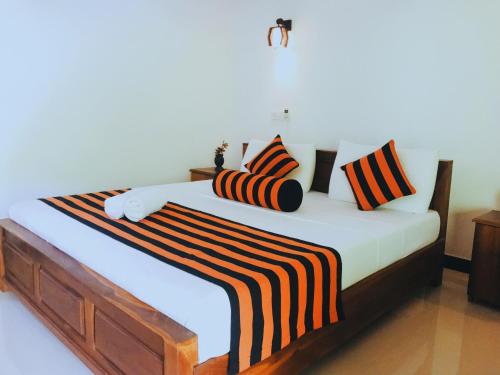 ein Schlafzimmer mit einem großen Bett mit gestreifter Bettwäsche und Kissen in der Unterkunft Sigiriya Ranasinghe Nature Villa in Sigiriya