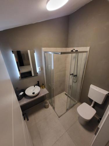 uma casa de banho com um chuveiro, um WC e um lavatório. em Apartmani J&I em Pakoštane